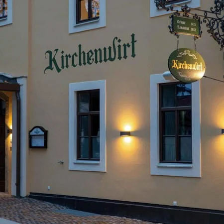 Der Kirchenwirt in Wörgl, Außenansicht der Fassade mit der Beleuchtung bei Dämmerung